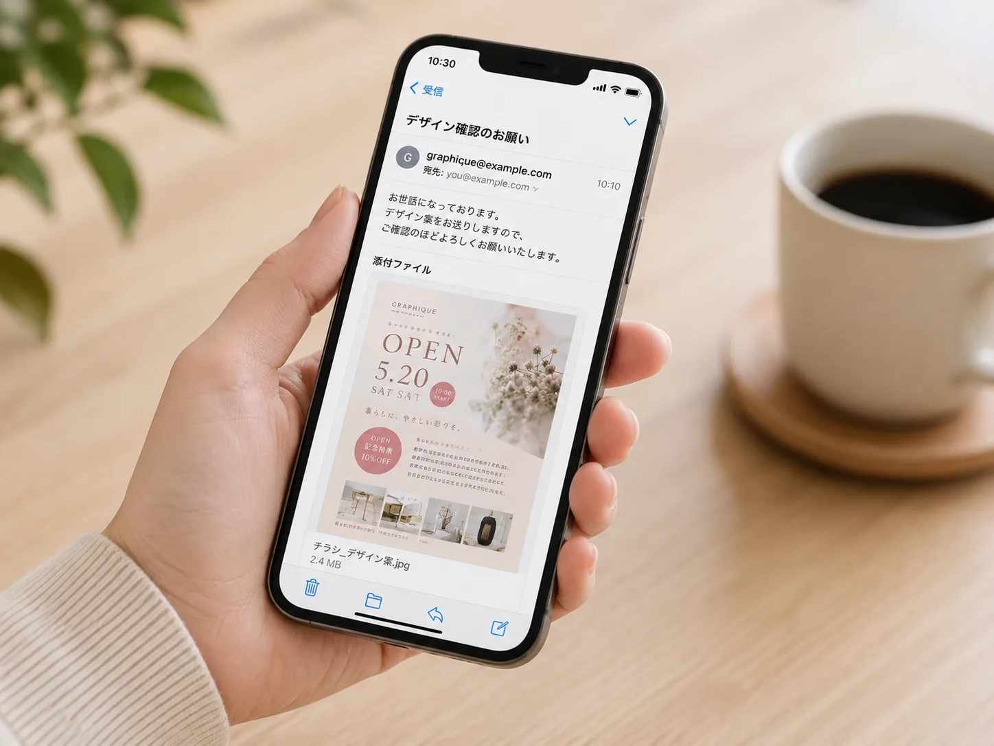 スマホでメール添付の確認用デザイン画像を見ているシーン